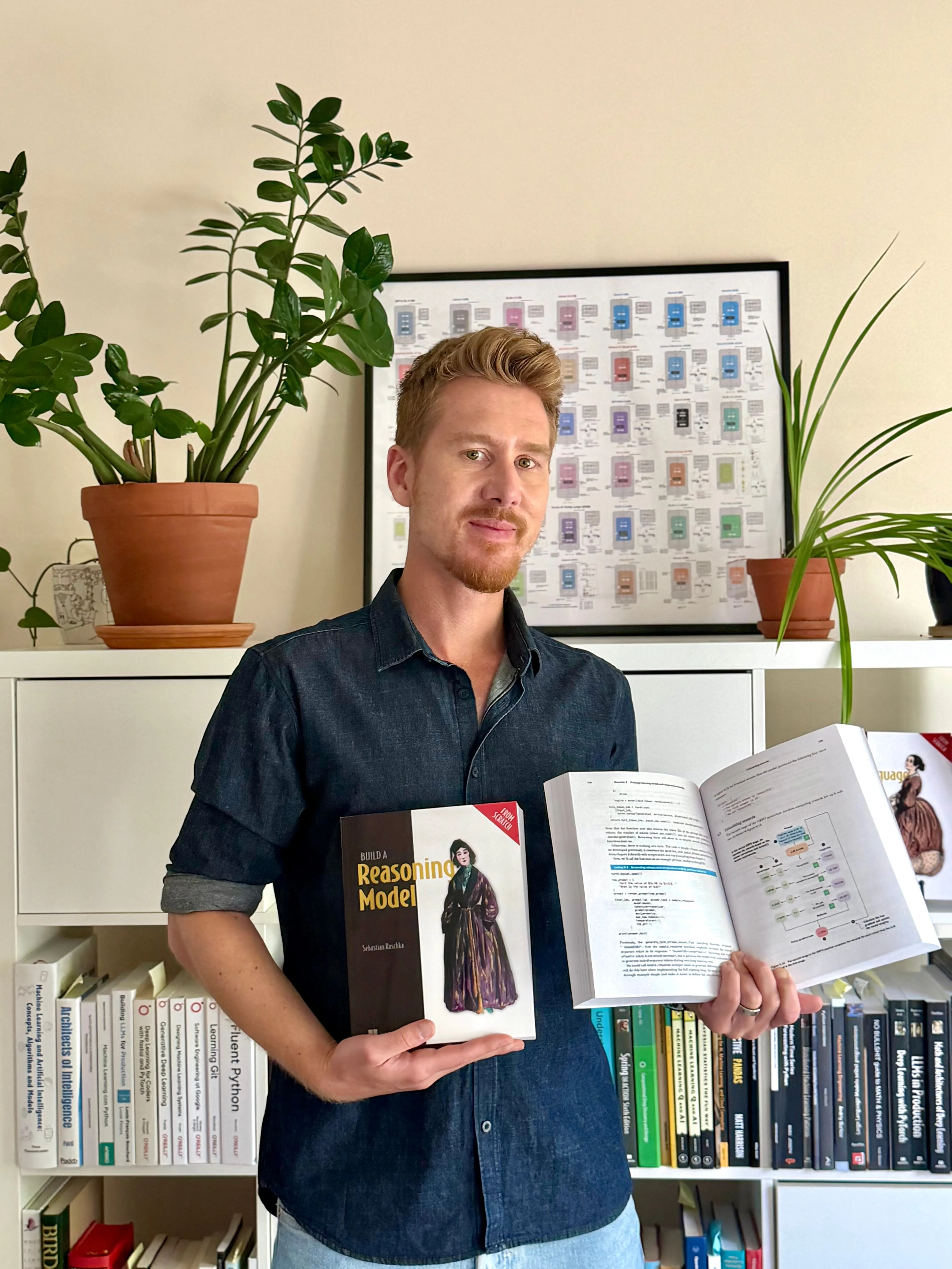 Sebastian Raschka holding the first printed copies of Build a Reasoning Model From Scratch in front of a bookshelf